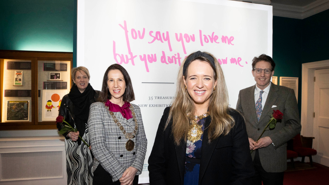 Four people pictured at opening of a National Museums NI and Little Museum of Dublin exhibition holding roses