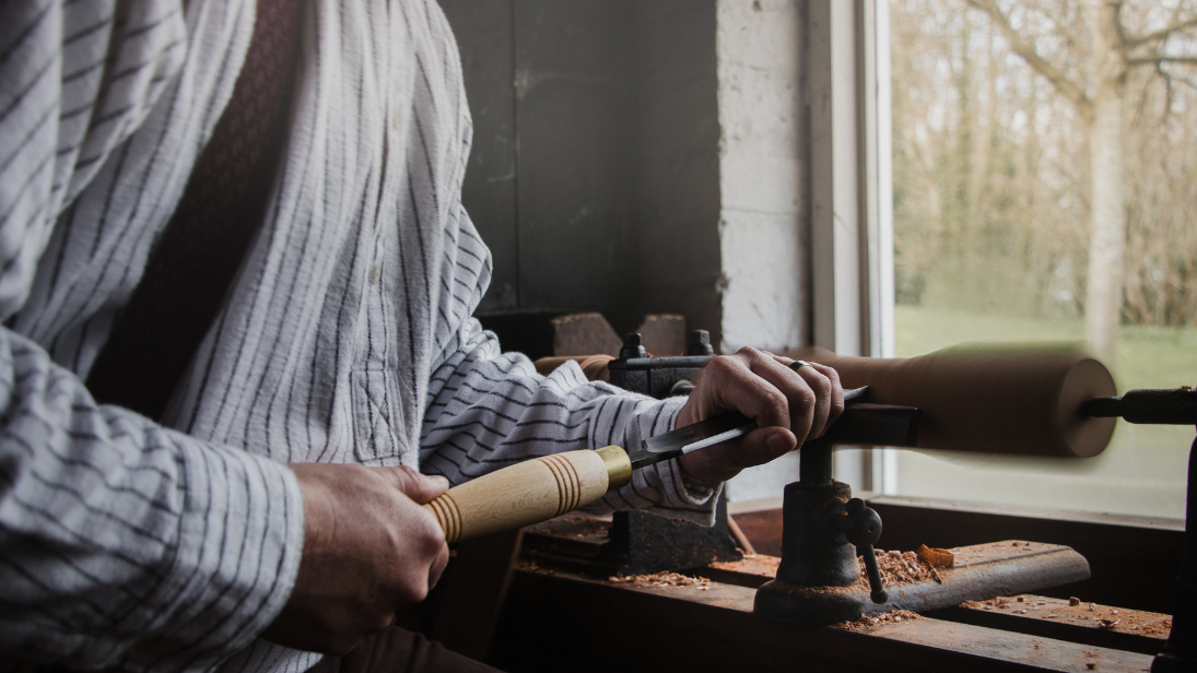 A man is using a carving tool on a piece of wood.