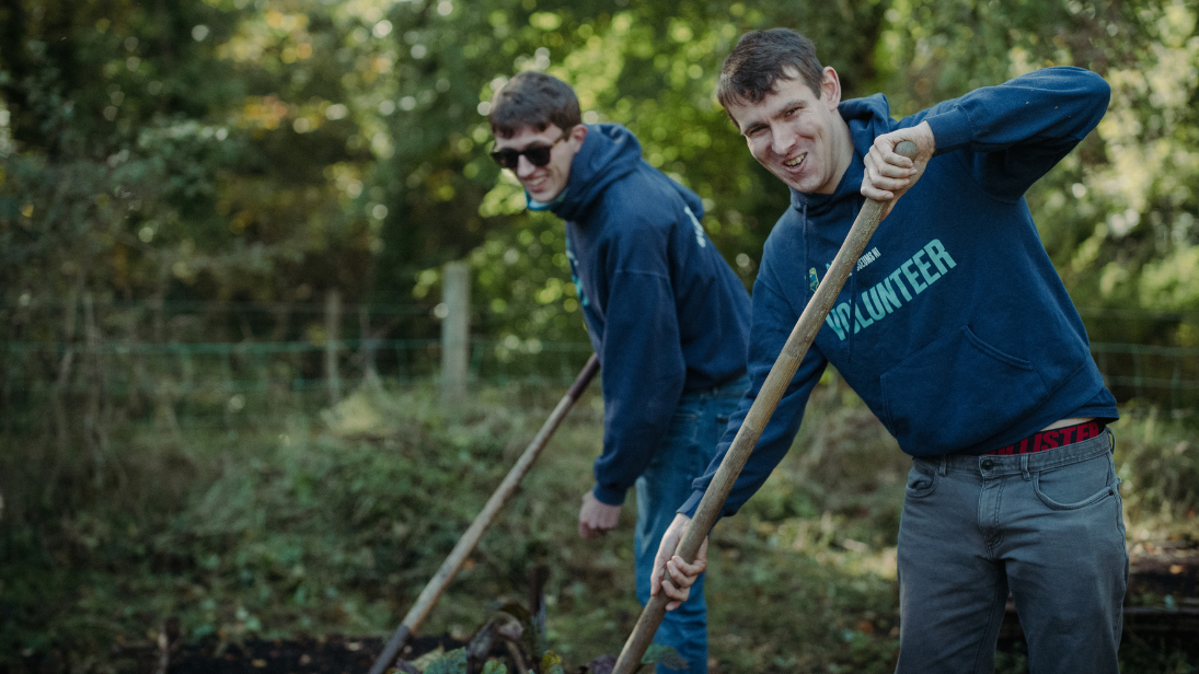 Two men digging and smiling at the camera at ulster folk museum 