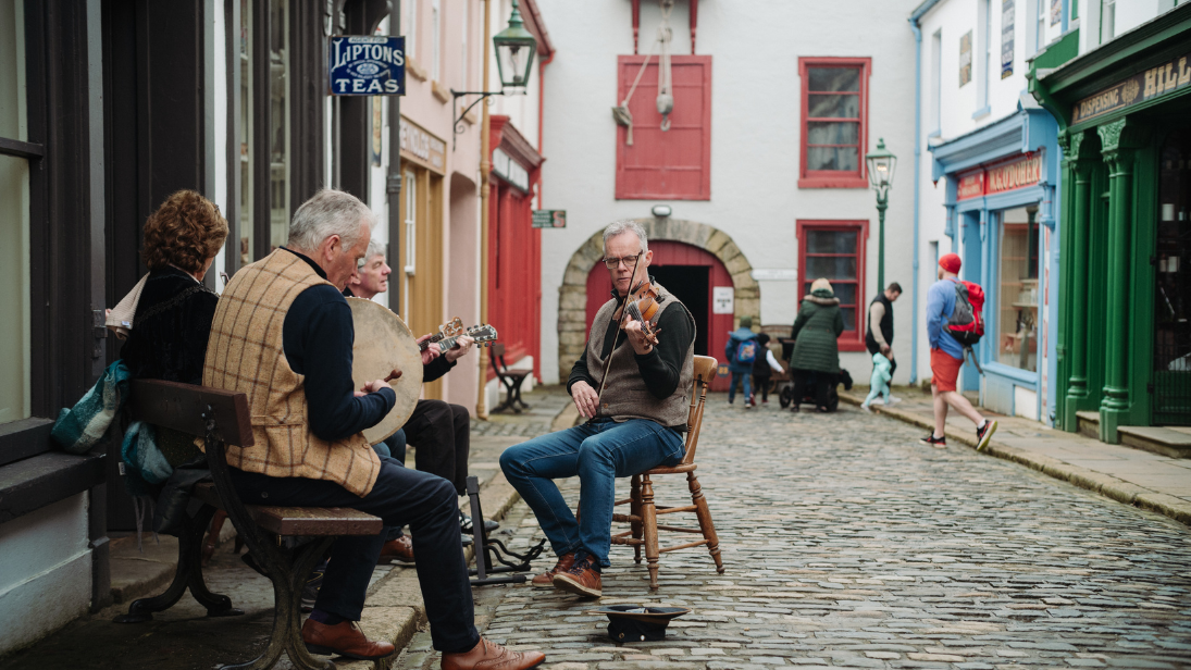 a group of trad musicians playing on american street in the folk park 