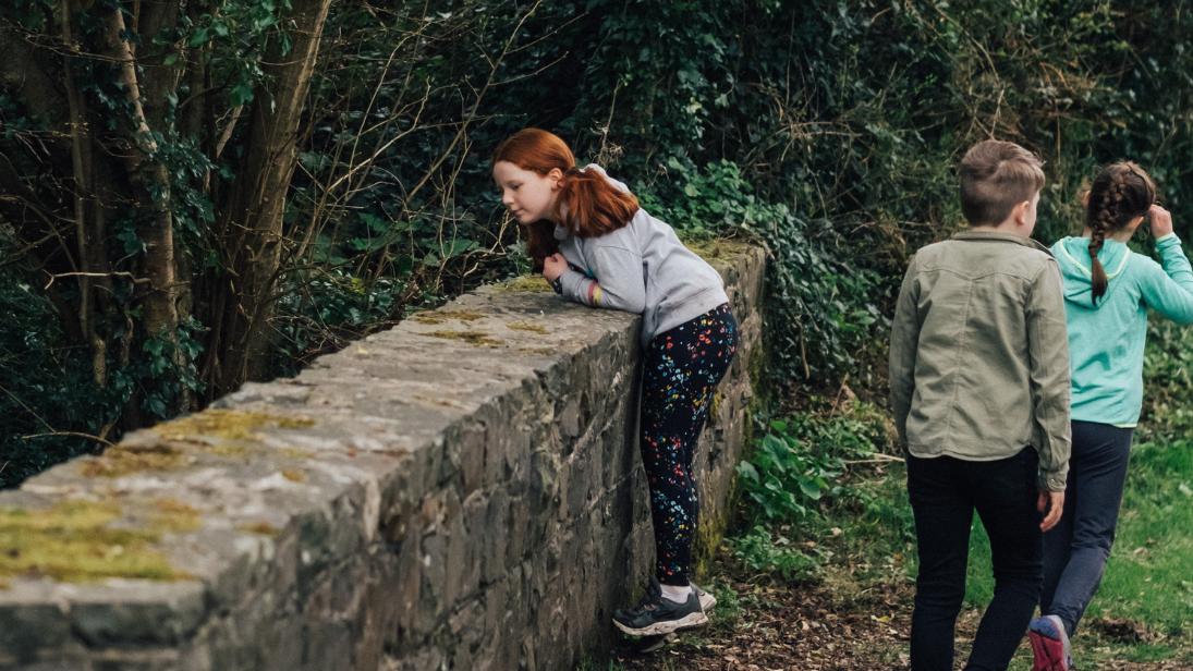 a girl peeking over a bridge at ulster folk museum 