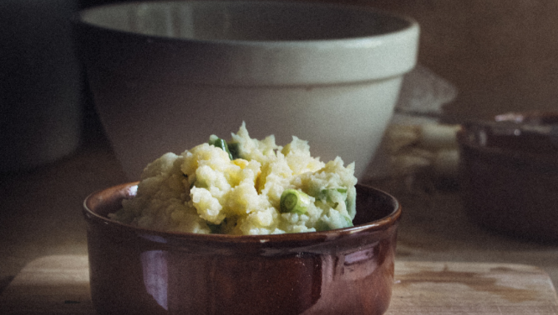 Champ served in a brown ceramic bowl on a wooden bench