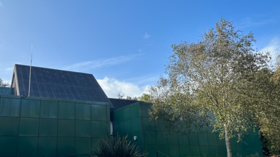 A green building stands against a blue sky.