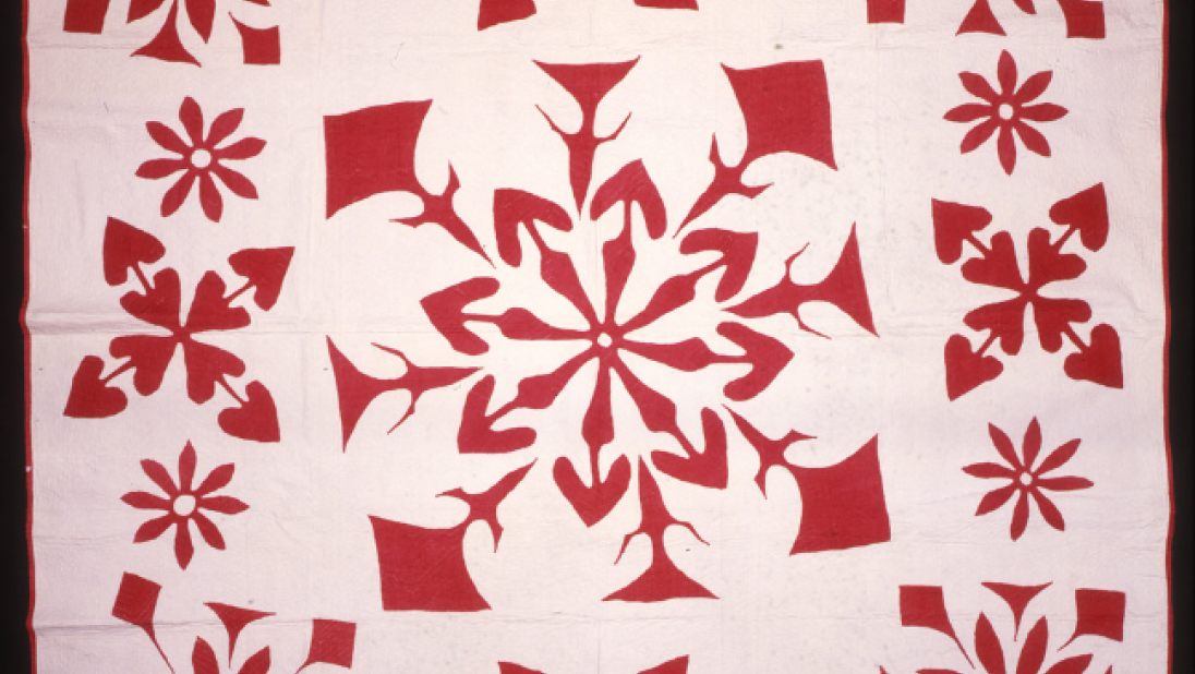 A white and red quilt with patterns like snowflakes on it.