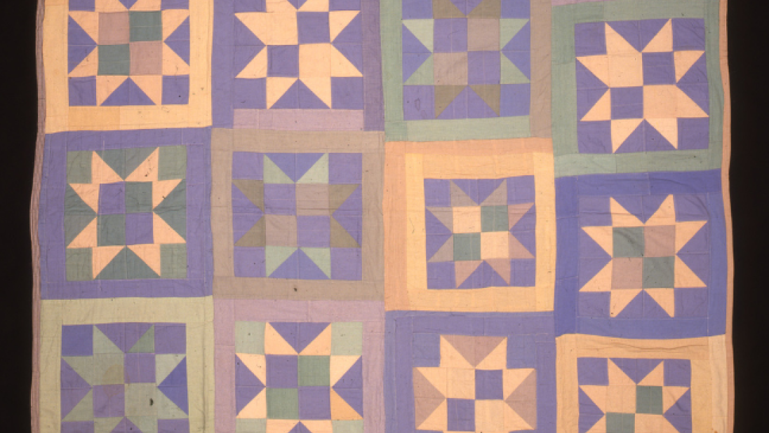 A colourful quilt with purples, blues, and oranges in squares with different patterns. 