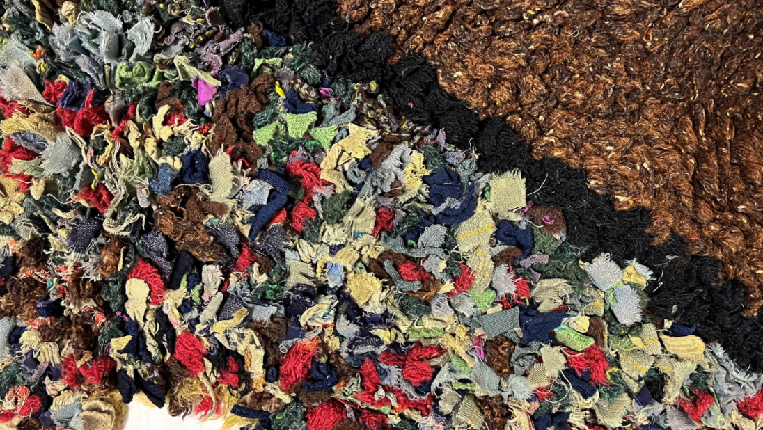 A detail shot of a rug. We can see a multicolour section with a hole. The outer section is brown.