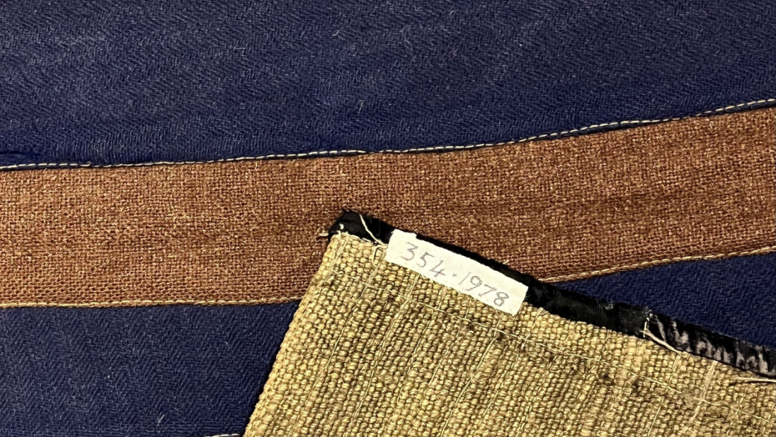 A striped rag rug showing the backing material, which is burlap.