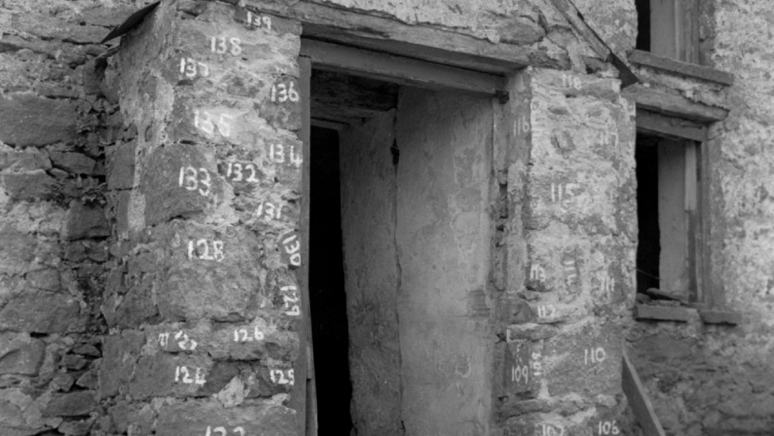 A black and white photograph of a farm building with its bricks numbered.