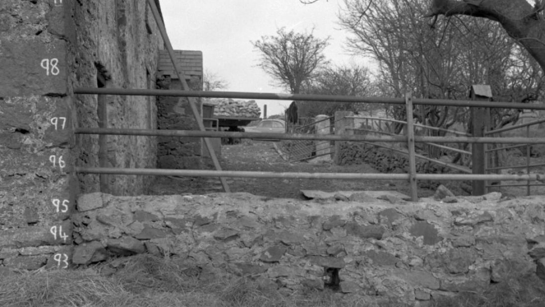 A black and white photograph of a farm building with its bricks numbered.