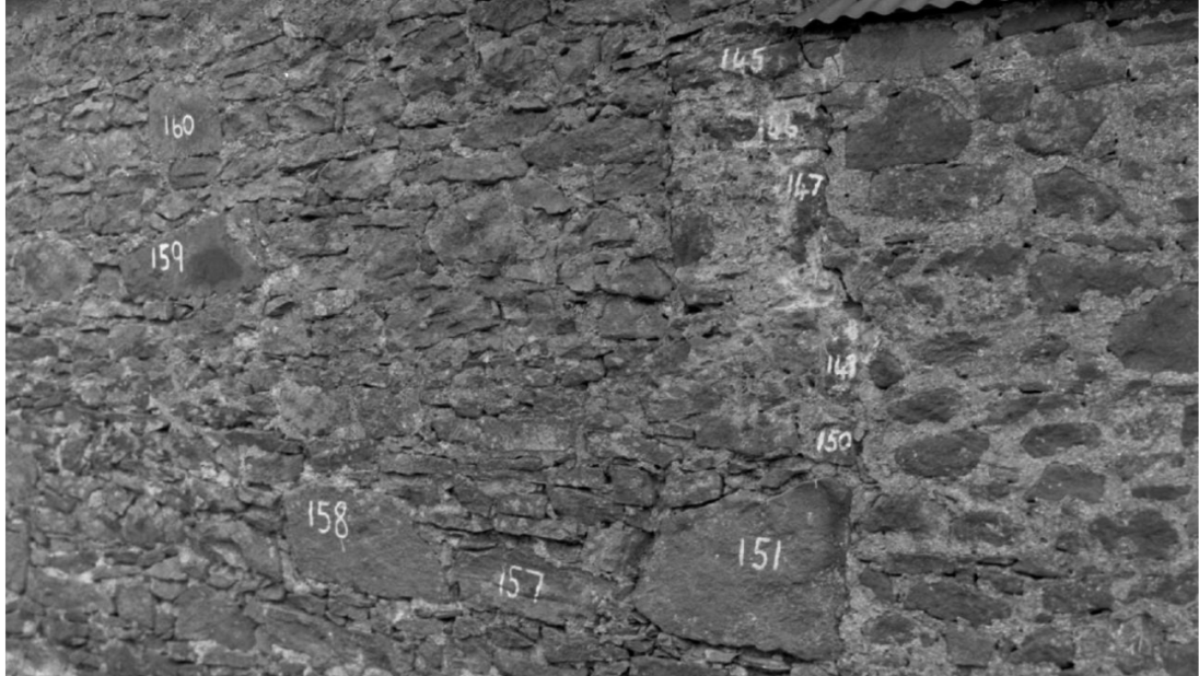A black and white photograph of a farm building with its bricks numbered.