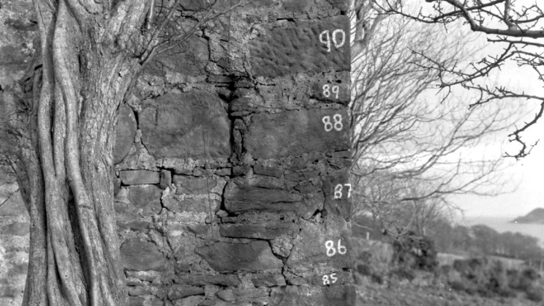 A black and white photograph of a farm building with its bricks numbered.