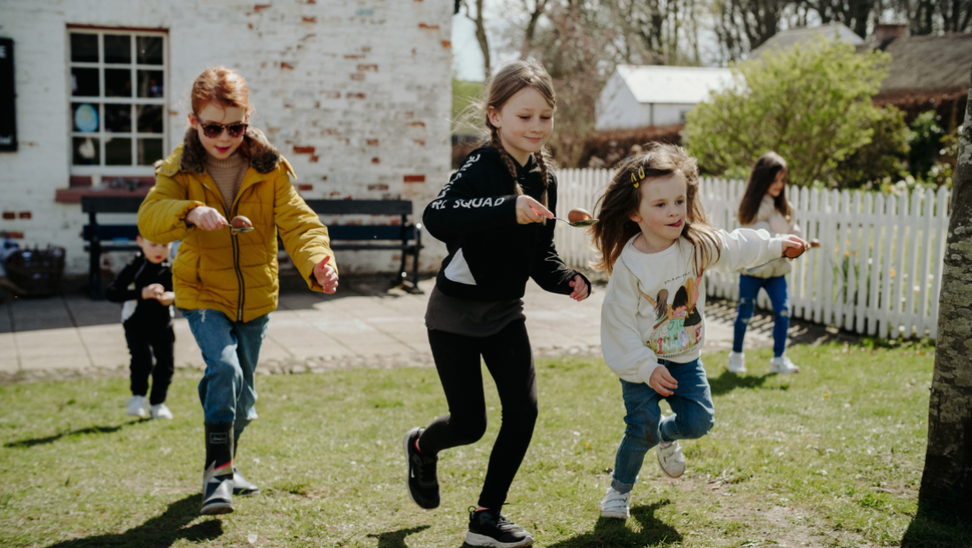 three girls playing an egg and spoon race