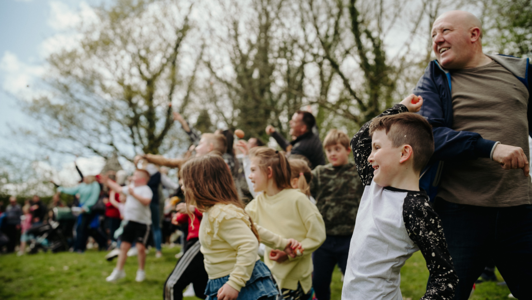 a group of people throwing eggs as part of a egg rolling easter event 