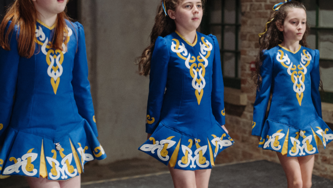 three girls irish dancing in blue traditional costume