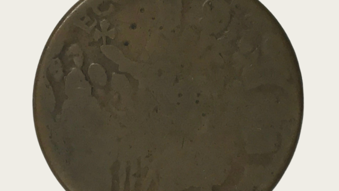 An old, worn coin. An image of St. Patrick holding a three leaf clover is just visible.