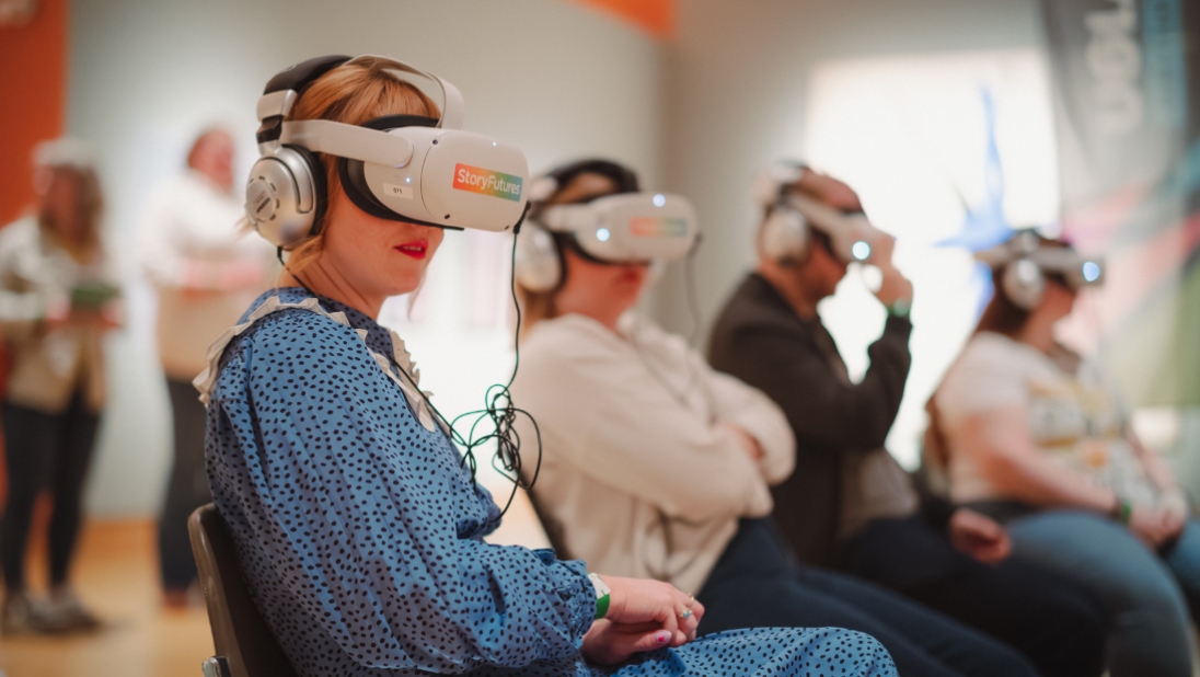 Four people sitting inside an art gallery with VR headsets on.