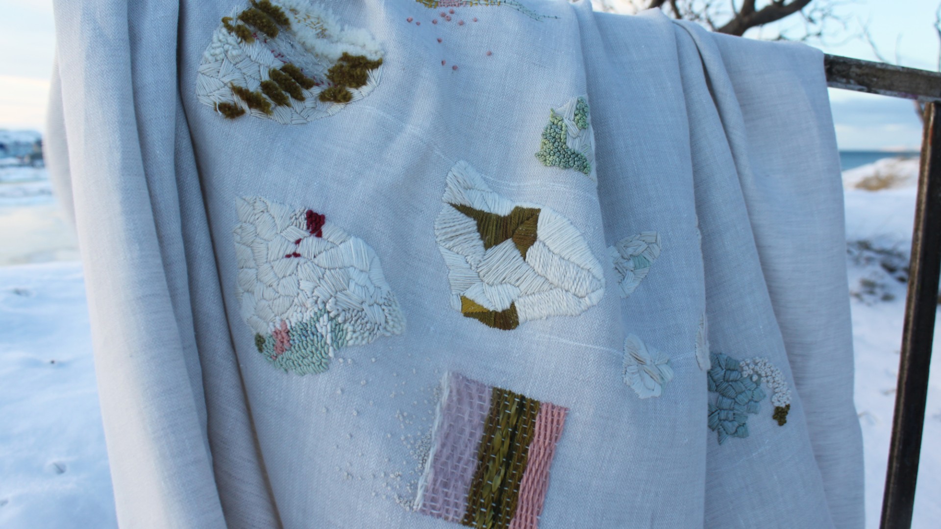 An installation view of a colourfully embroidered linen.