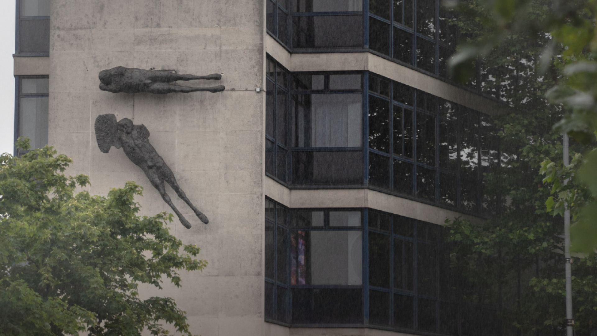 A building with two sculptures attached, looking like angels or flying figures. 