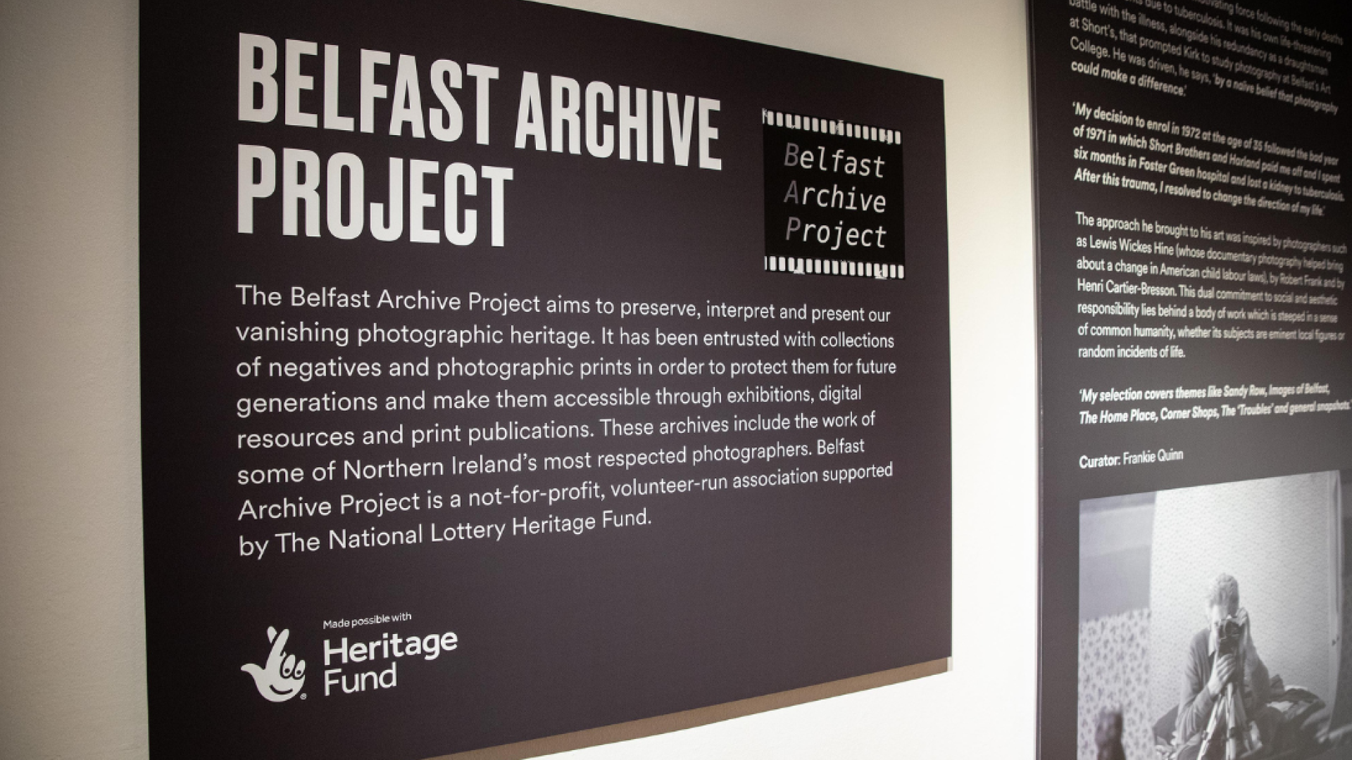 A photo of black and white panels on a wall, the main panel in focus says 'Belfast Archive Project' with a blurb of white text on a black background plus National Lottery Heritage Fund logo and Belfast Archive Project logo.