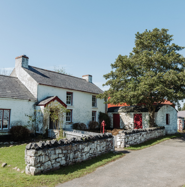A farm house with a sprawling front garden sits in the sun