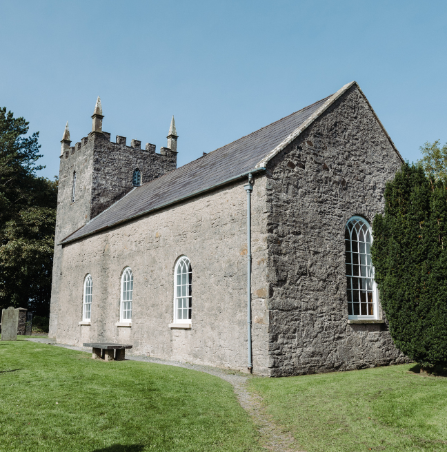 A large grey stone church with a graveyard visible.