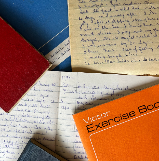 Collection of diaries open and closed, layered on top of eachother