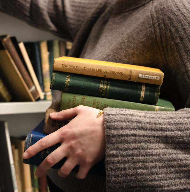 Hand holding a stack of books in a library