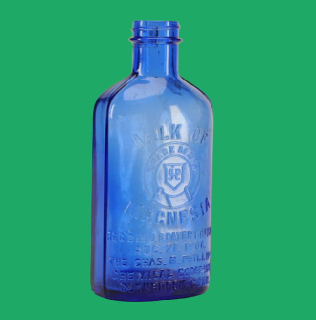 Blue bottle of milk of magnesia, on a green background