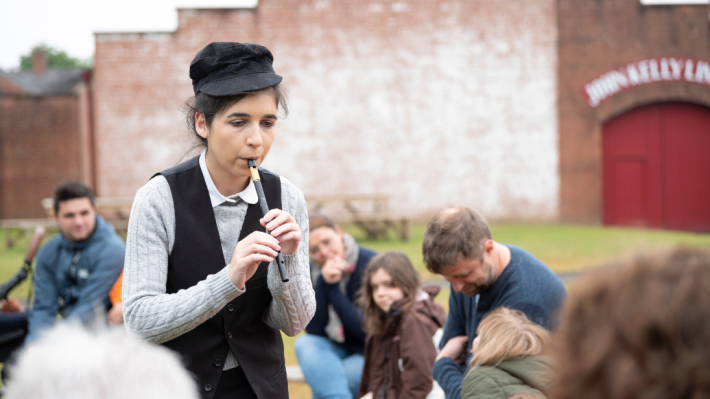 An image of a lady playing a tin whistle at Ulster Folk Museum