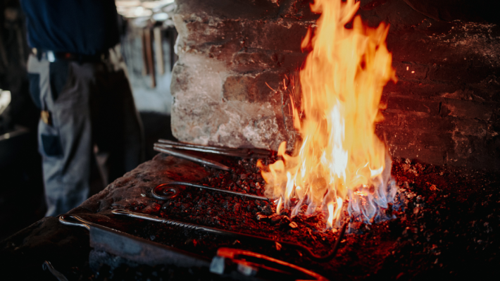 An image of a forge fire, with iron tools resting on the surface.