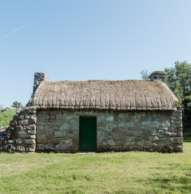A small stone cottage sits in a large open space