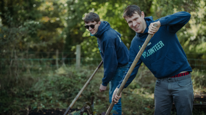 Two men digging and smiling at the camera at ulster folk museum 