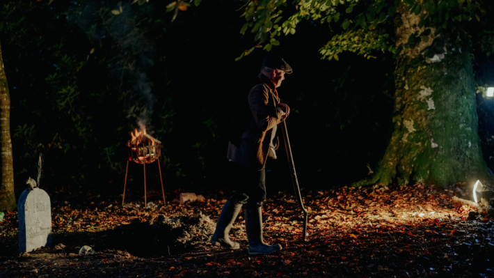 A man in a dimly lit graveyard at the folk park