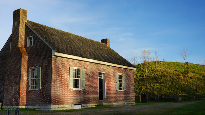 A red brick house stands in the setting sun.