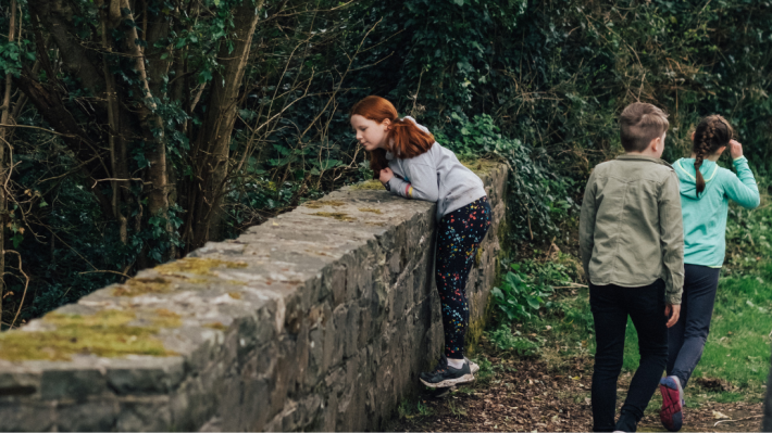 A red haired child looking over a bridge