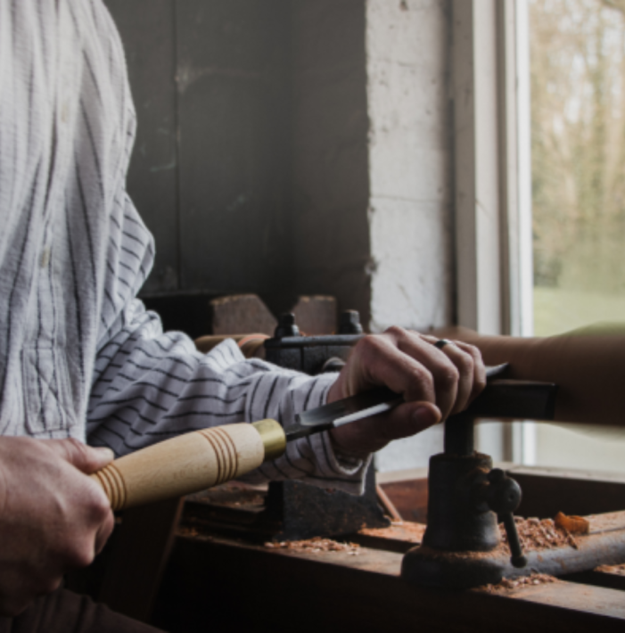 Heritage carpenter turning wood on a lathe at the Ulster Folk Museum