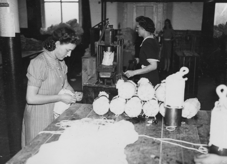 Women packing small parachutes into containers