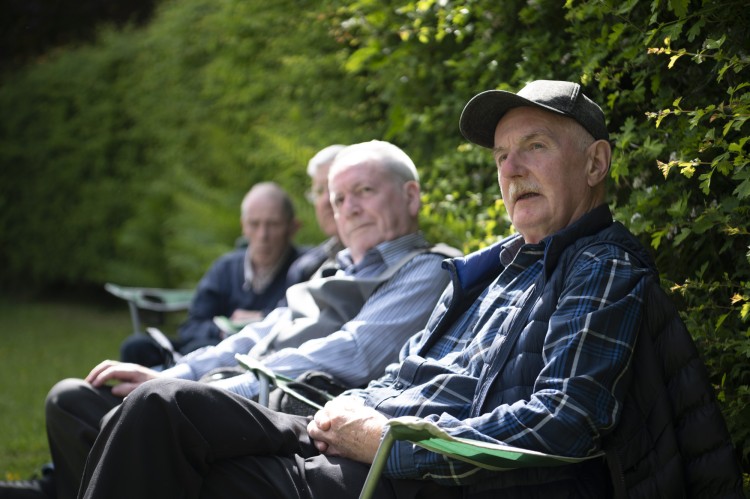 Four people sat by a hedge enjoying the festival