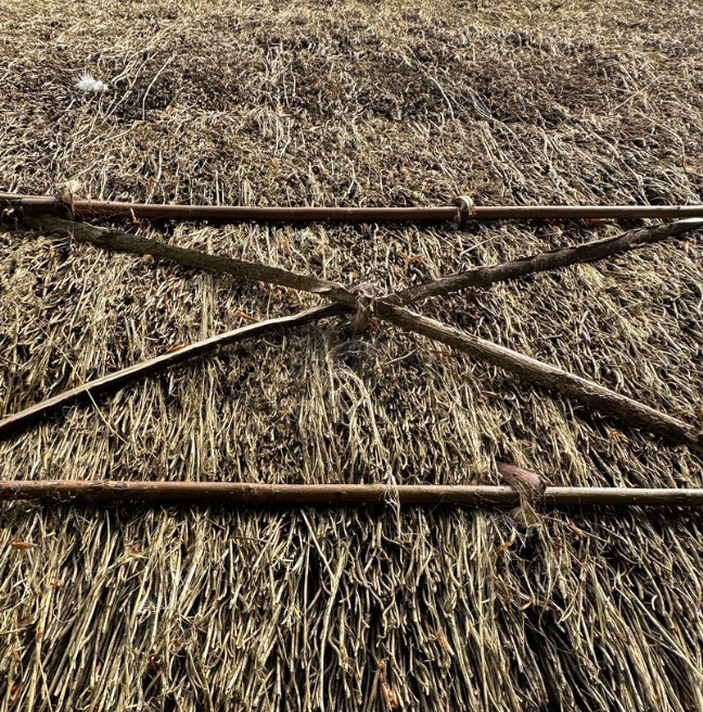 The eave of a thatched roof showing the scollops for decoration.