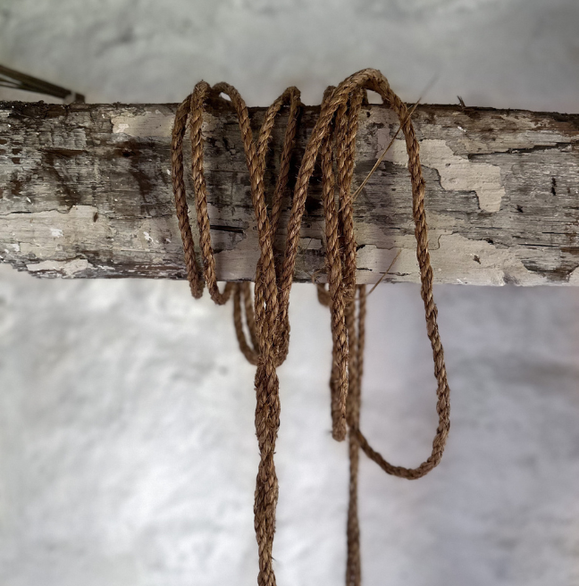 A close-up of a rope strung around a wooden post. 