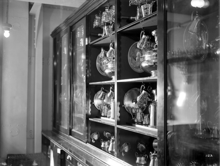 A black and white image of a cabinet filled with glass dinner ware. 