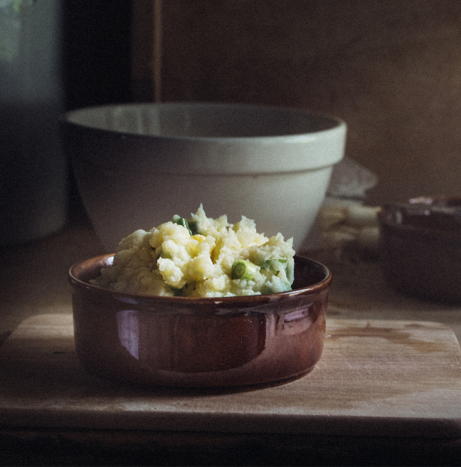 Champ served in a brown ceramic bowl on a wooden bench