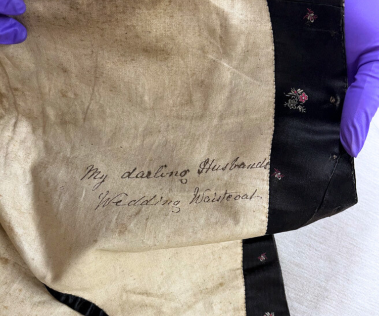 On the inside of a waistcoat, the message 'my darling husband's wedding waistcoat'.