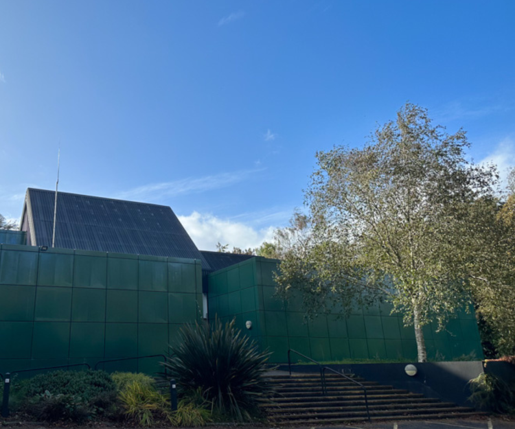 A green building stands against a blue sky.