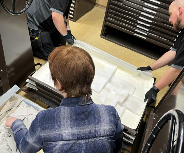 Three people sit sorting through textiles.