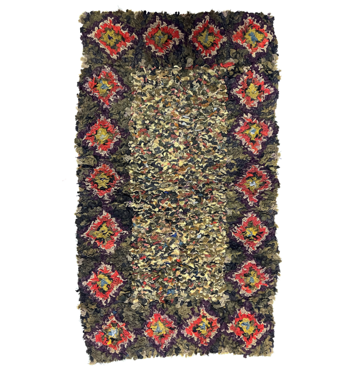 A rectangular rug. The inner part of the rug is a multi-coloured rectangle. The outer rectangle is blue with colourful diamond shaped decorations.