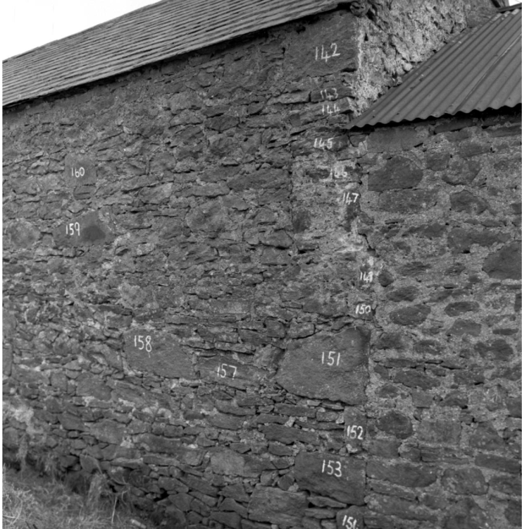 A black and white photograph of a farm building with its bricks numbered.