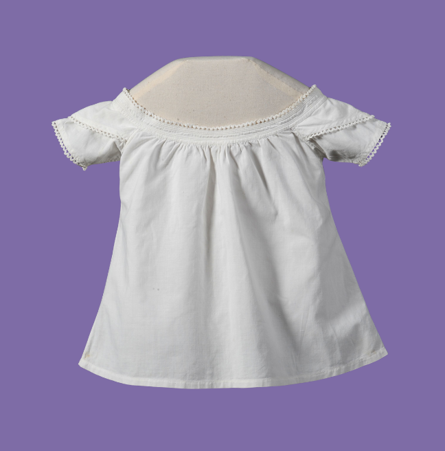 Old children's white dress on a purple background