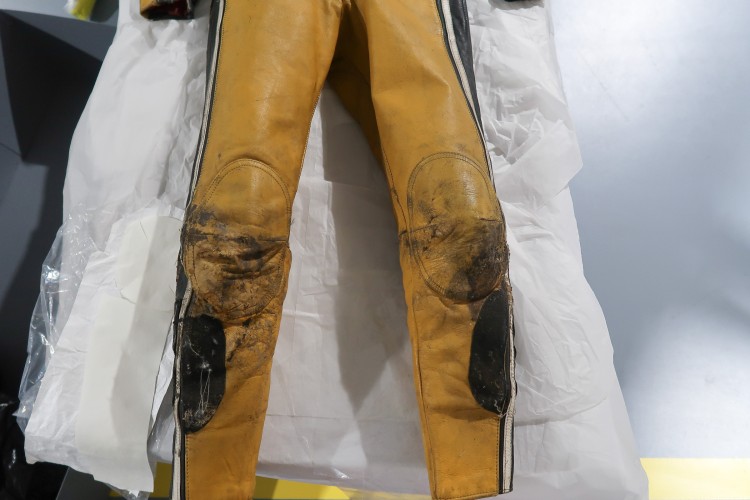 The legs of a yellow and black jumpsuit. The kneepads have undergone conservation and look cleaner than they did in the picture above.