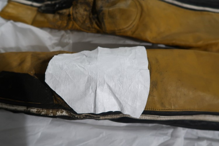A close up of the knee of a yellow and black jumpsuit with a piece of white cloth over it.